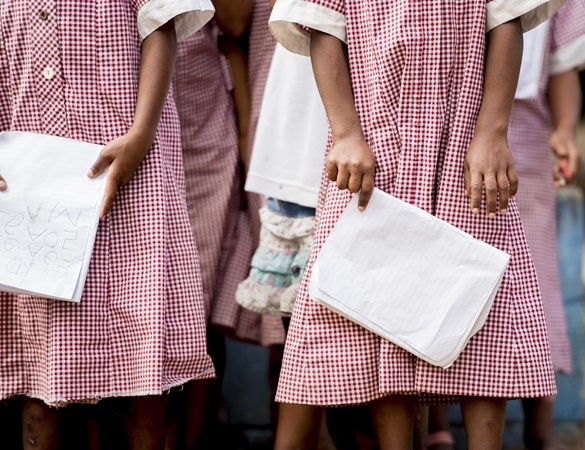 Close shot of kids standing in lines holding their notebooks with a blurred background